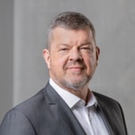 Mann im Anzug vor grauem Hintergrund.