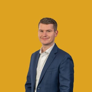 Diego Meuli im Anzug vor gelbem Hintergrund.