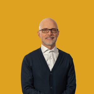 Mann mit Brille vor gelbem Hintergrund.