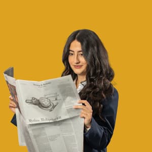 Frau liest Zeitung vor gelbem Hintergrund.