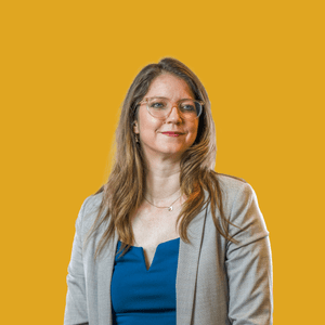 Frau mit Brille vor gelbem Hintergrund.