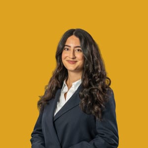 Person in Anzug vor gelbem Hintergrund.