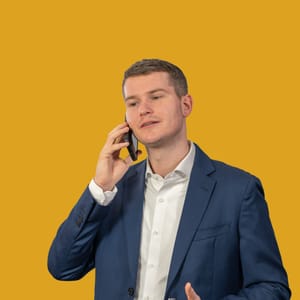 Diego Meuli im Anzug telefoniert vor gelbem Hintergrund.