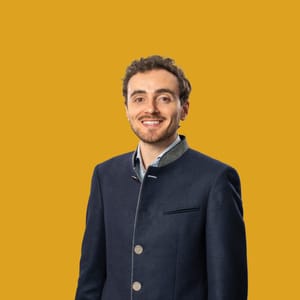 Mann im Anzug vor gelbem Hintergrund.