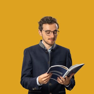 Mann im Anzug, der ein Buch liest, vor gelbem Hintergrund.