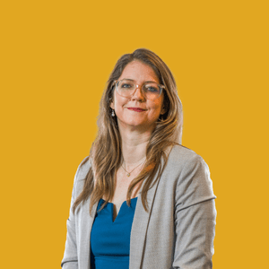 Frau mit Brille vor gelbem Hintergrund lächelnd.