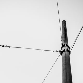 Schwarz-weiss Foto eines Strommasts mit Drähten.