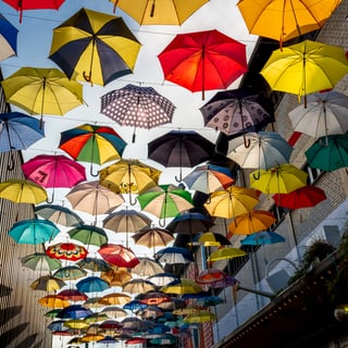 Viele bunte Regenschirme, die in der Luft hängen.