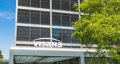 Modernes Bürogebäude mit Visana-Logo bei blauem Himmel.