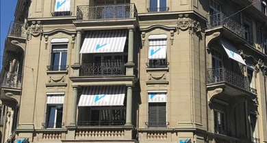 Historisches Gebäude mit Markisen und blauen Logos auf Fassade.