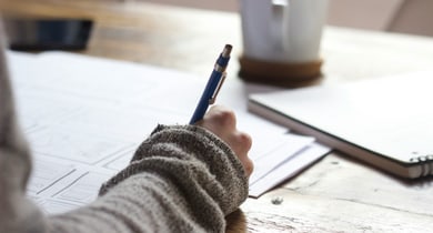 Hand schreibt mit einem Stift auf Papier.