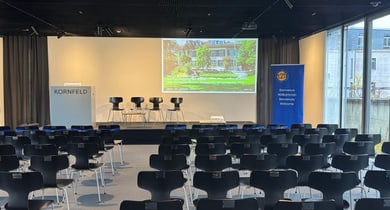 Konferenzraum mit Stuhlreihe und Präsentationsbildschirm.