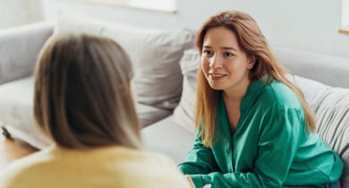 Zwei Personen sitzen auf einem Sofa und unterhalten sich.