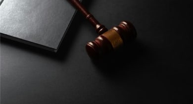 Richterhammer und Buch auf schwarzem Hintergrund.