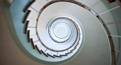 Blick nach oben in ein spiralförmiges Treppenhaus.
