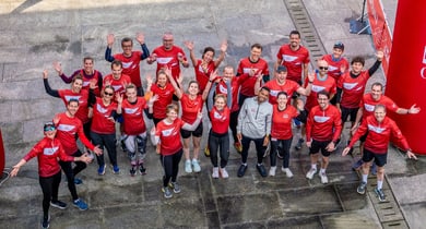 Gruppe von Personen in roten Sporttrikots hebt die Arme.