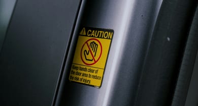 Warnschild an Autotür mit Hinweis, Hände fernzuhalten.