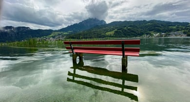 Rote Bank im überfluteten See mit Bergen im Hintergrund.