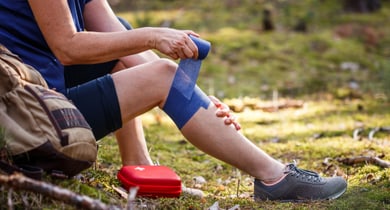 Verletzte Wandererin, die einen elastischen Verband an ihr Knie legt