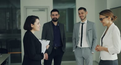 Gruppe von vier Personen in geschäftlicher Kleidung im Gespräch.
