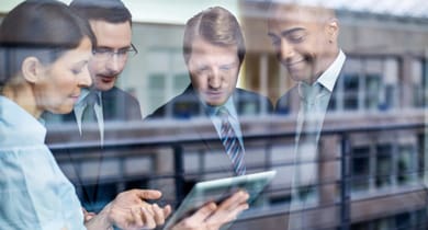 Geschäftstreffen hinter Glas, Hauptfokus auf ein Tablet.