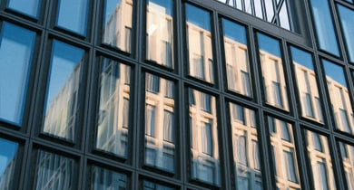 Moderne Glasfassade eines Gebäudes mit Reflexionen.