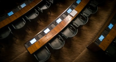 Holzbankreihen mit Bildschirmen und Sitzen in einem Konferenzraum.