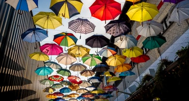 Viele bunte Regenschirme, die in der Luft hängen.