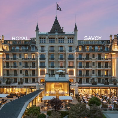 Abendansicht eines grossen, beleuchteten Hotels mit Garten.