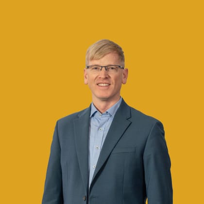 Mann mit Anzug vor gelbem Hintergrund.