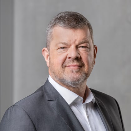 Mann im Anzug vor grauem Hintergrund.
