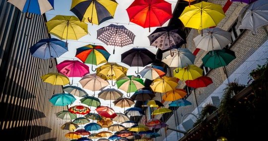 Viele bunte Regenschirme, die in der Luft hängen.
