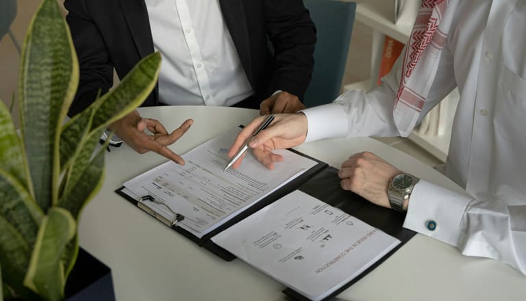 Zwei Personen besprechen Dokumente am Tisch.