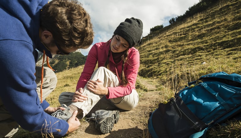 YOUNG MAN CARING FOR INJURED WOMAN ON HIKING TOUR