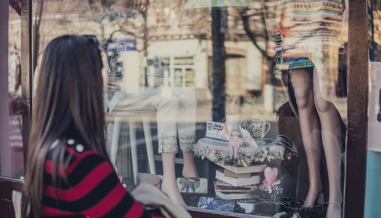 Frau vor Schaufenster Kleiderladen