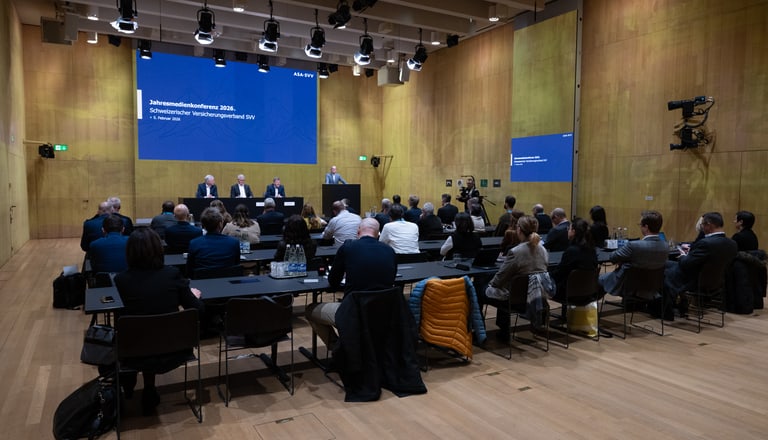 Konferenzraum mit Rednern und Publikum auf Stühlen.