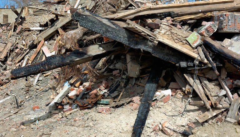 Trümmerhaufen aus verbranntem Holz und Ziegeln.