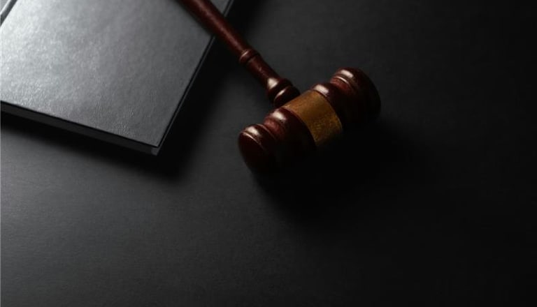 Richterhammer und Buch auf schwarzem Hintergrund.