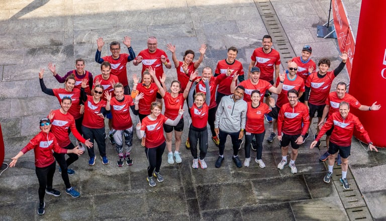 Gruppe von Personen in roten Sporttrikots hebt die Arme.