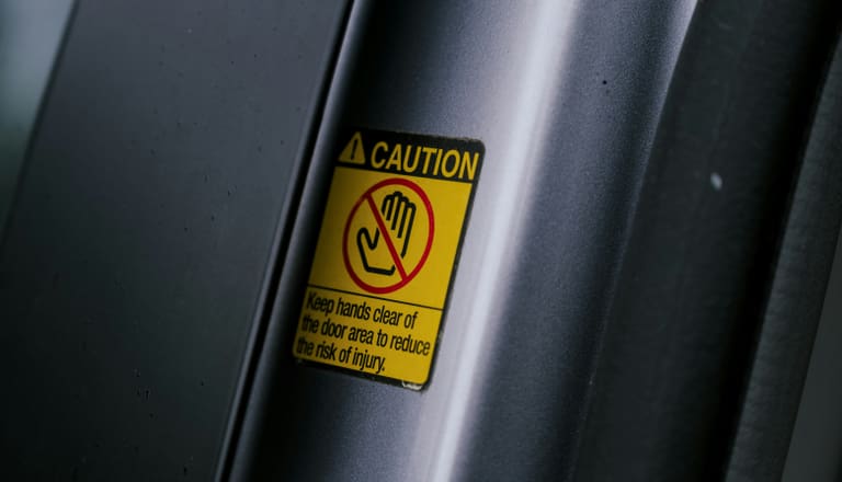 Warnschild an Autotür mit Hinweis, Hände fernzuhalten.