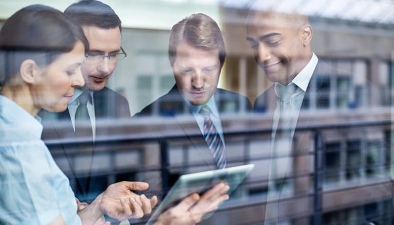 Geschäftstreffen hinter Glas, Hauptfokus auf ein Tablet.