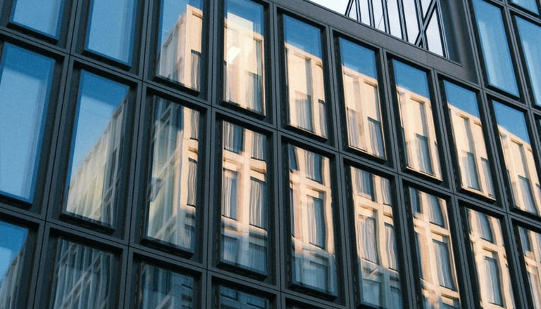 Moderne Glasfassade eines Gebäudes mit Reflexionen.
