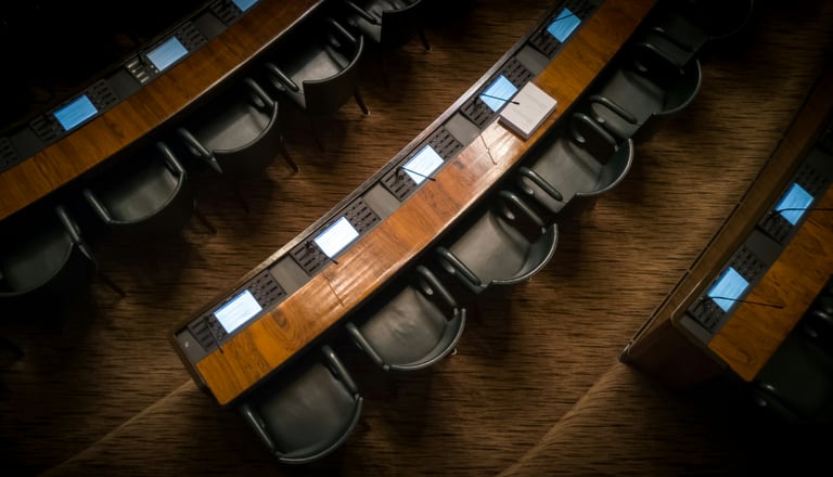 Holzbankreihen mit Bildschirmen und Sitzen in einem Konferenzraum.