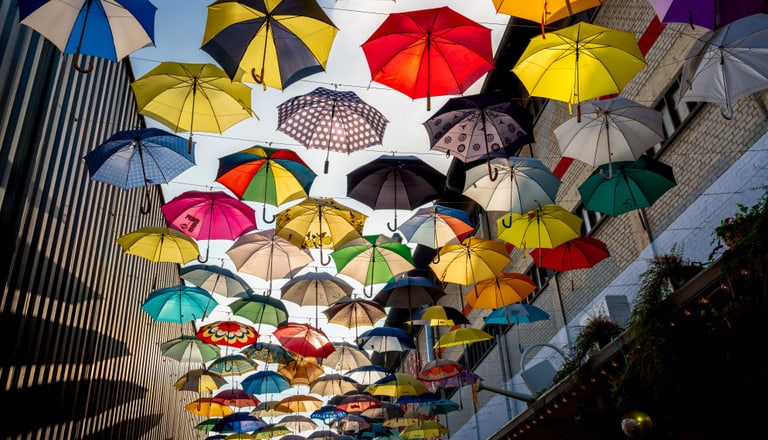 Viele bunte Regenschirme, die in der Luft hängen.