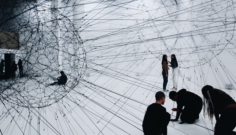 Personen sitzen in einem Netz-artigen Kunstwerk, das die Verknüpfung von finanziellen Daten symbolisiert. Foto von Alina Grubnyak (unsplash.com)