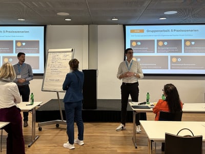 Teilnehmer bei einer Gruppenpräsentation in einem Konferenzraum.