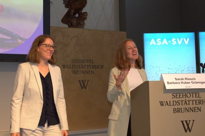 Zwei Personen stehen bei einem Rednerpult in einem Konferenzraum.