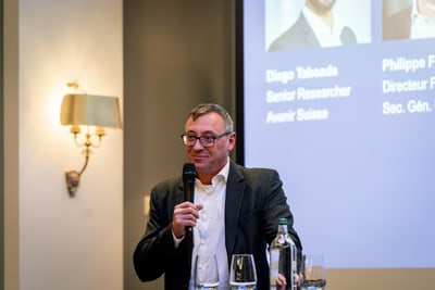 Mann mit Mikrofon bei Präsentation an Rednerpult mit Flaschen und Gläsern.