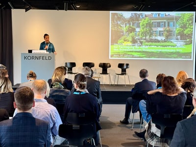 Vortragender auf Veranstaltung vor Publikum mit Präsentation auf Leinwand.