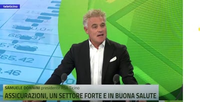 Mann spricht in Fernsehstudio mit Grafik im Hintergrund.